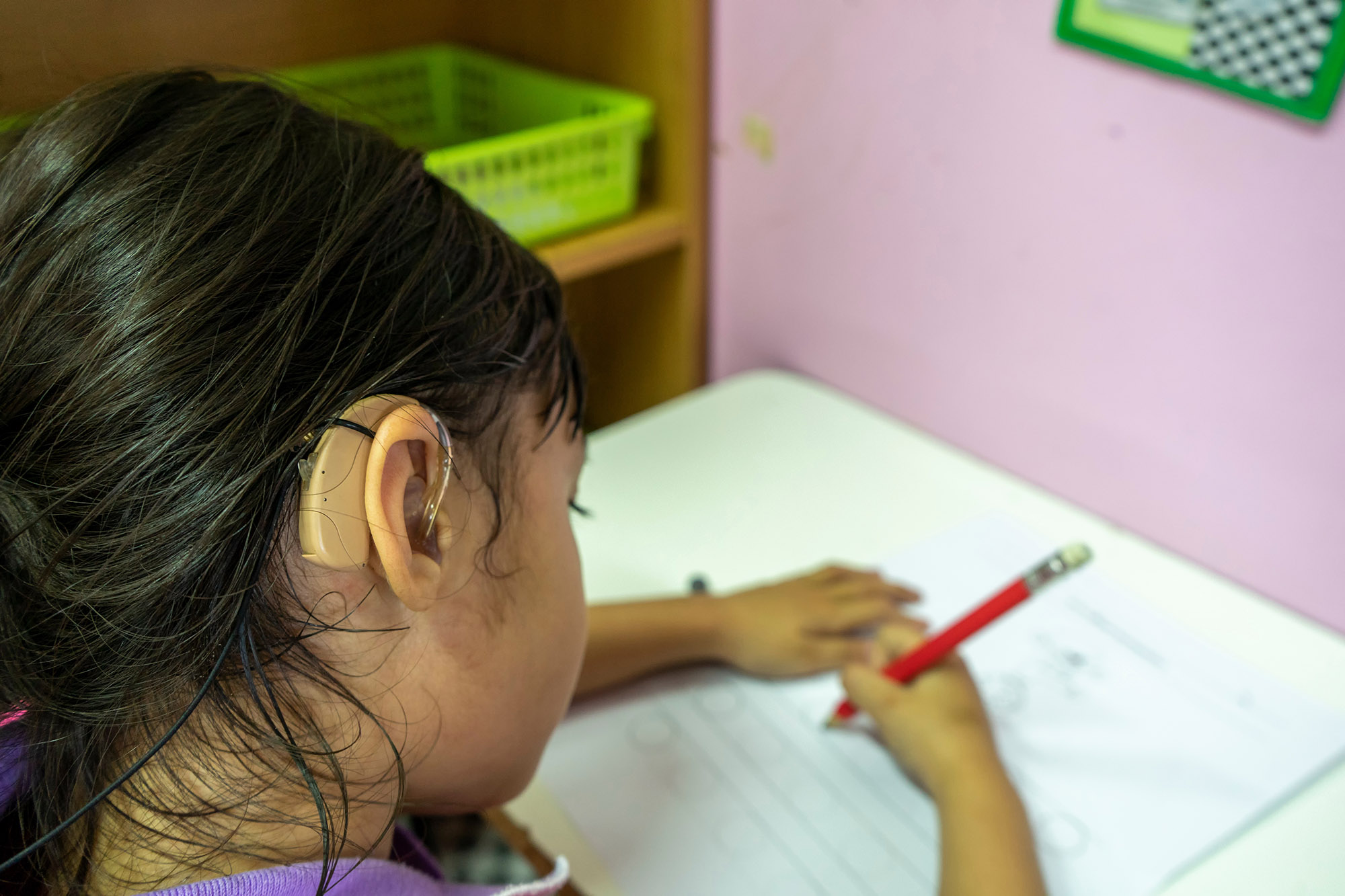 Asian girl with hearing aid doing schoolwork